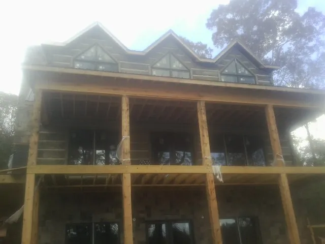 Dormers and porch framing on a large log home under construction — Roof Coating work by our crew in Nunnelly